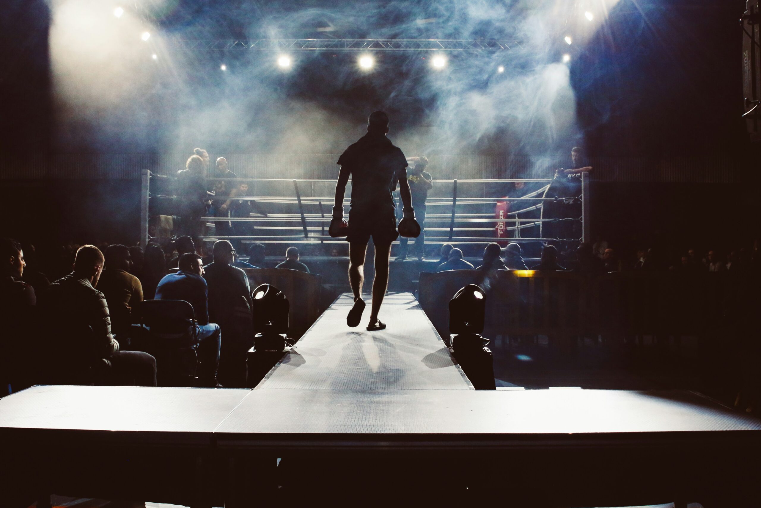 Boxer walking toward the ring under the lights before a fight.